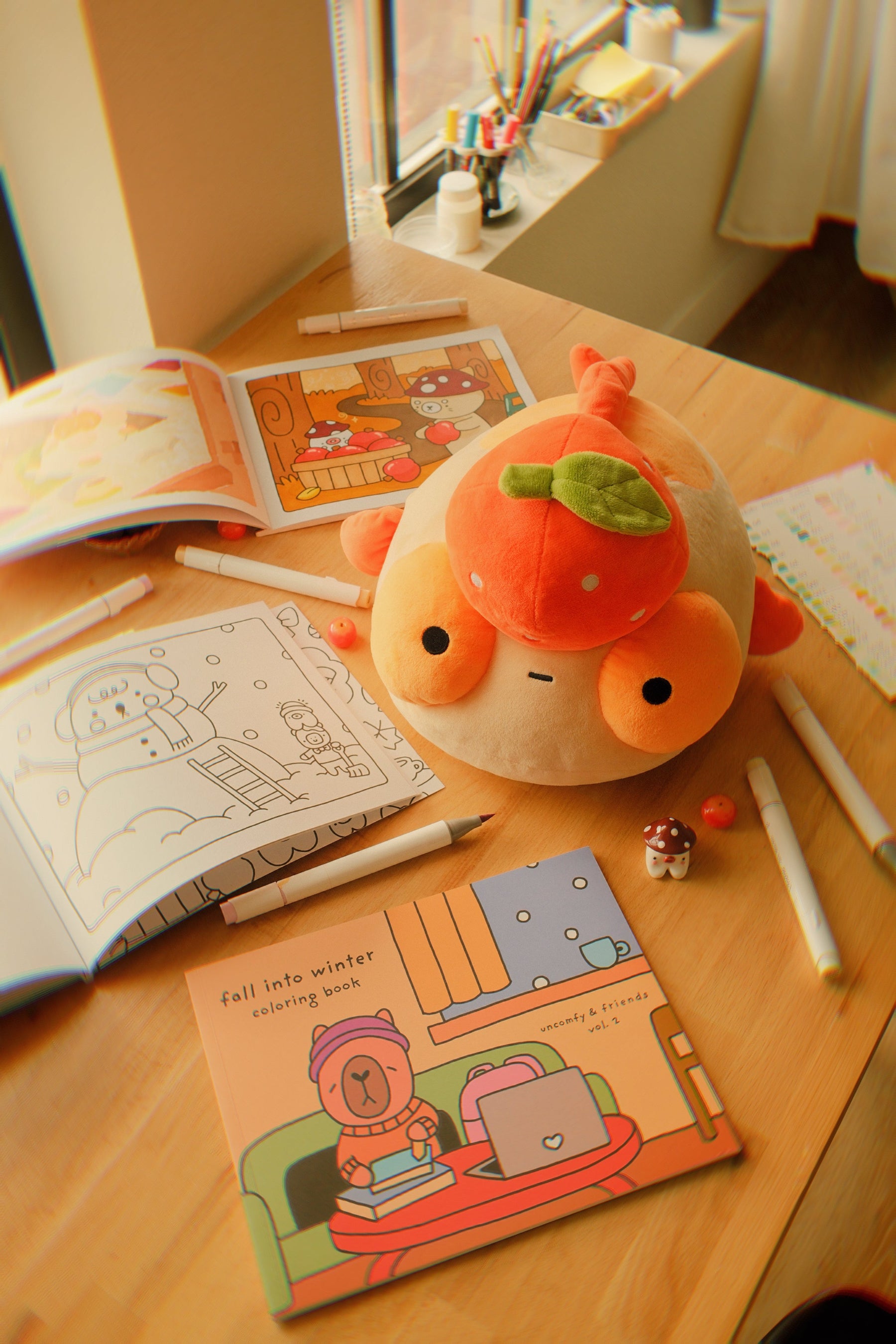 Tangerine Maxine on a table with the Fall into Winter coloring book and some pens