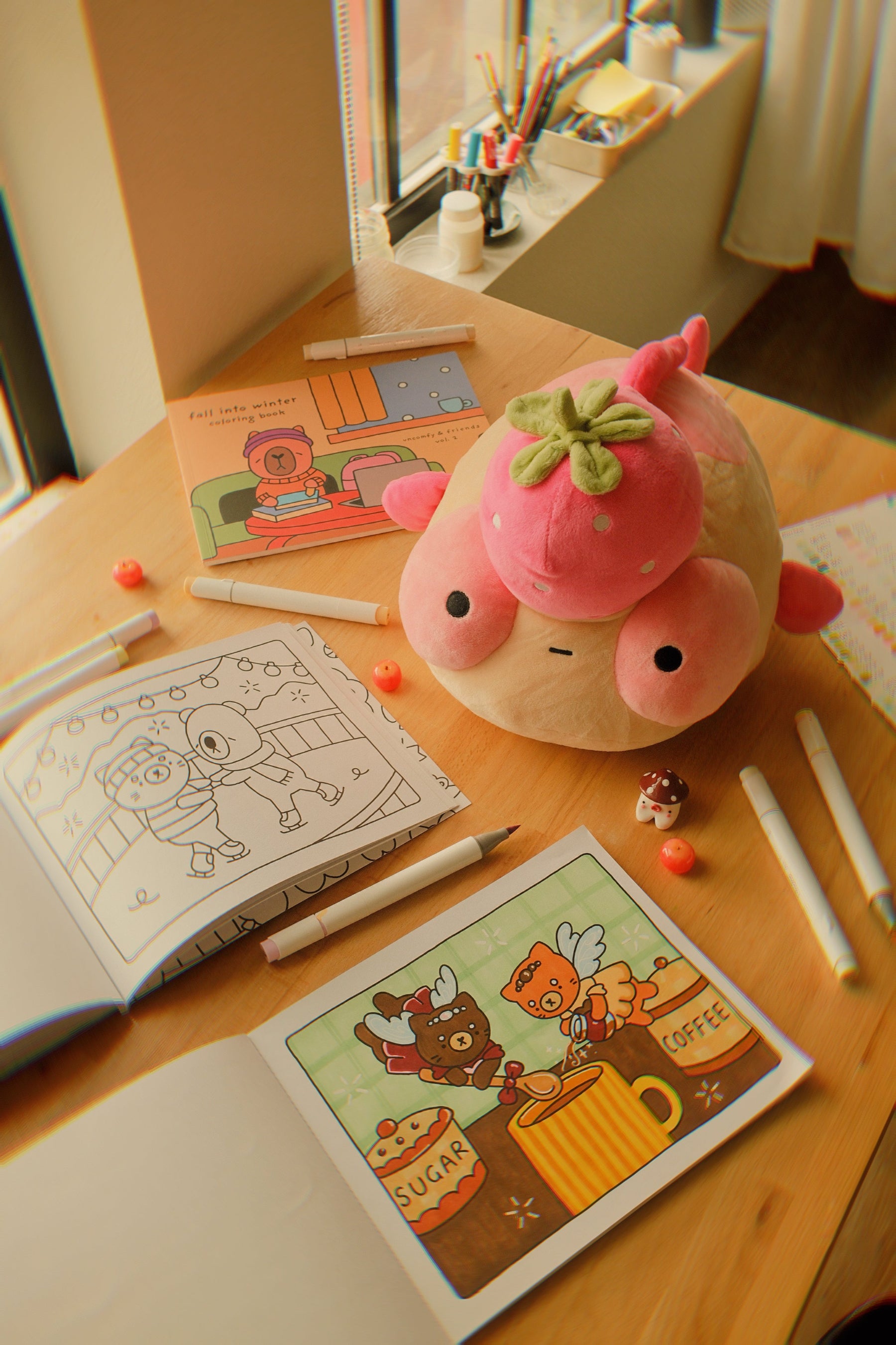 Pink plush Maxine on a table with coloring books and markers