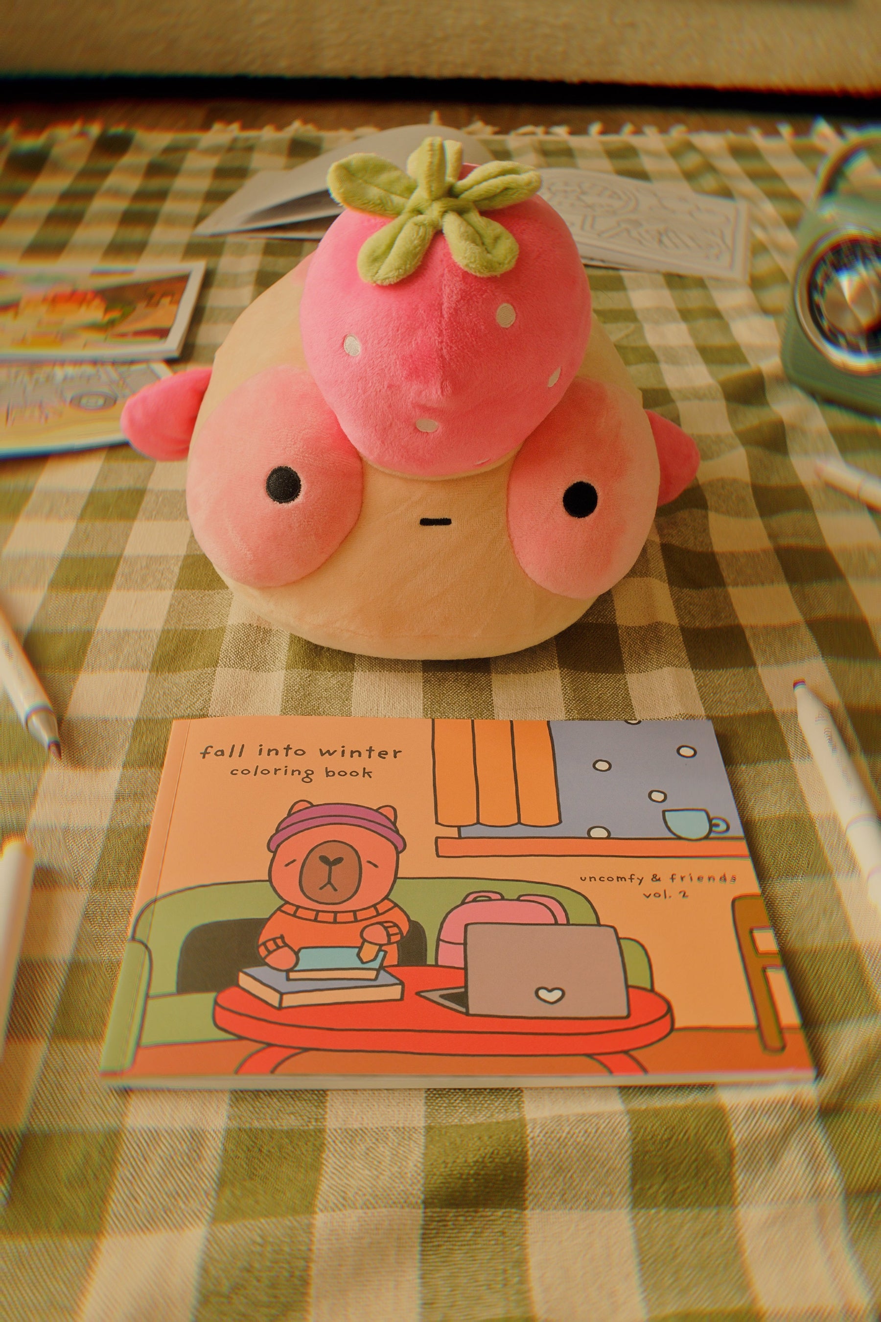 Plush Maxine on a checkered tablecloth with a coloring book titled 'Fall into Winter'.