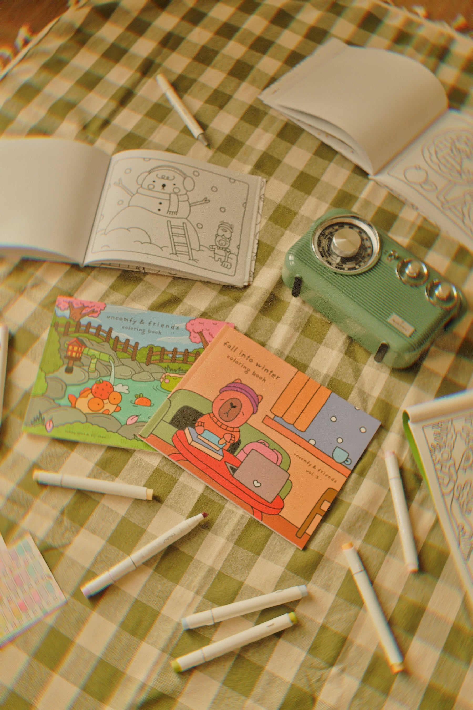 Coloring books and markers on a green checkered tablecloth